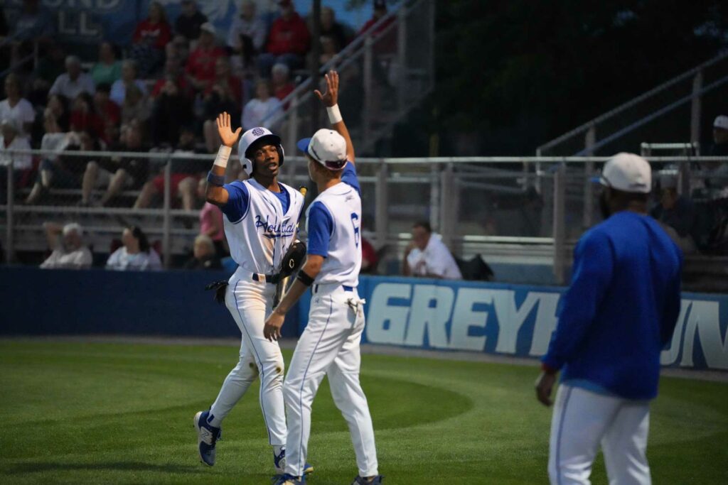 Boys high-fiving at a baseball game